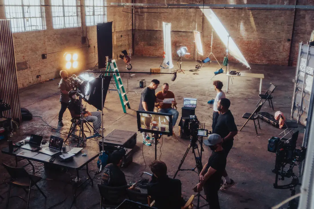 A crew working on a set inside a sunlit warehouse